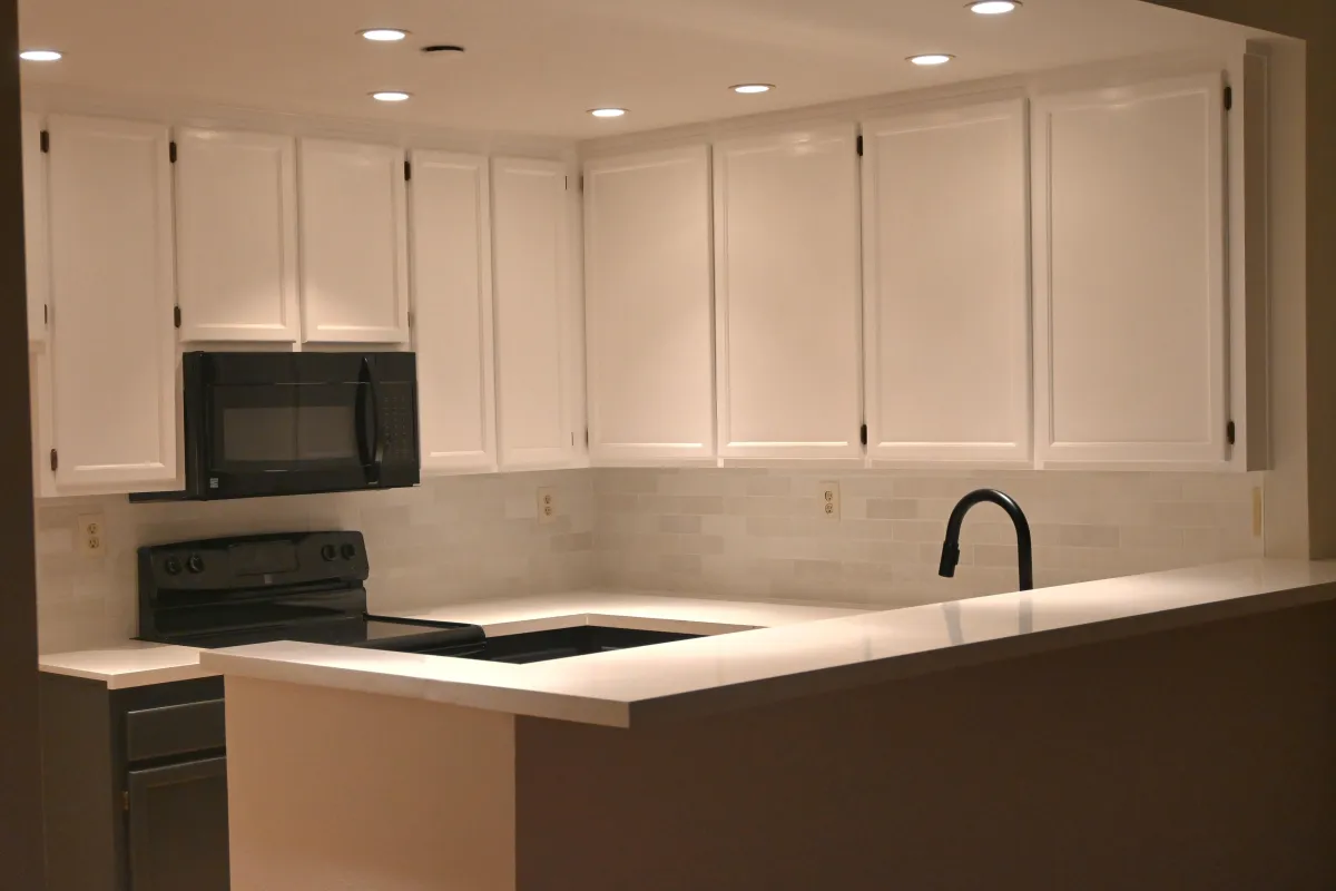 Kitchen remodel Featuring white cabinets with black hinges, black base cabinet, peninsula with white quartz, white quartz countertops in Corte Madera, CA.