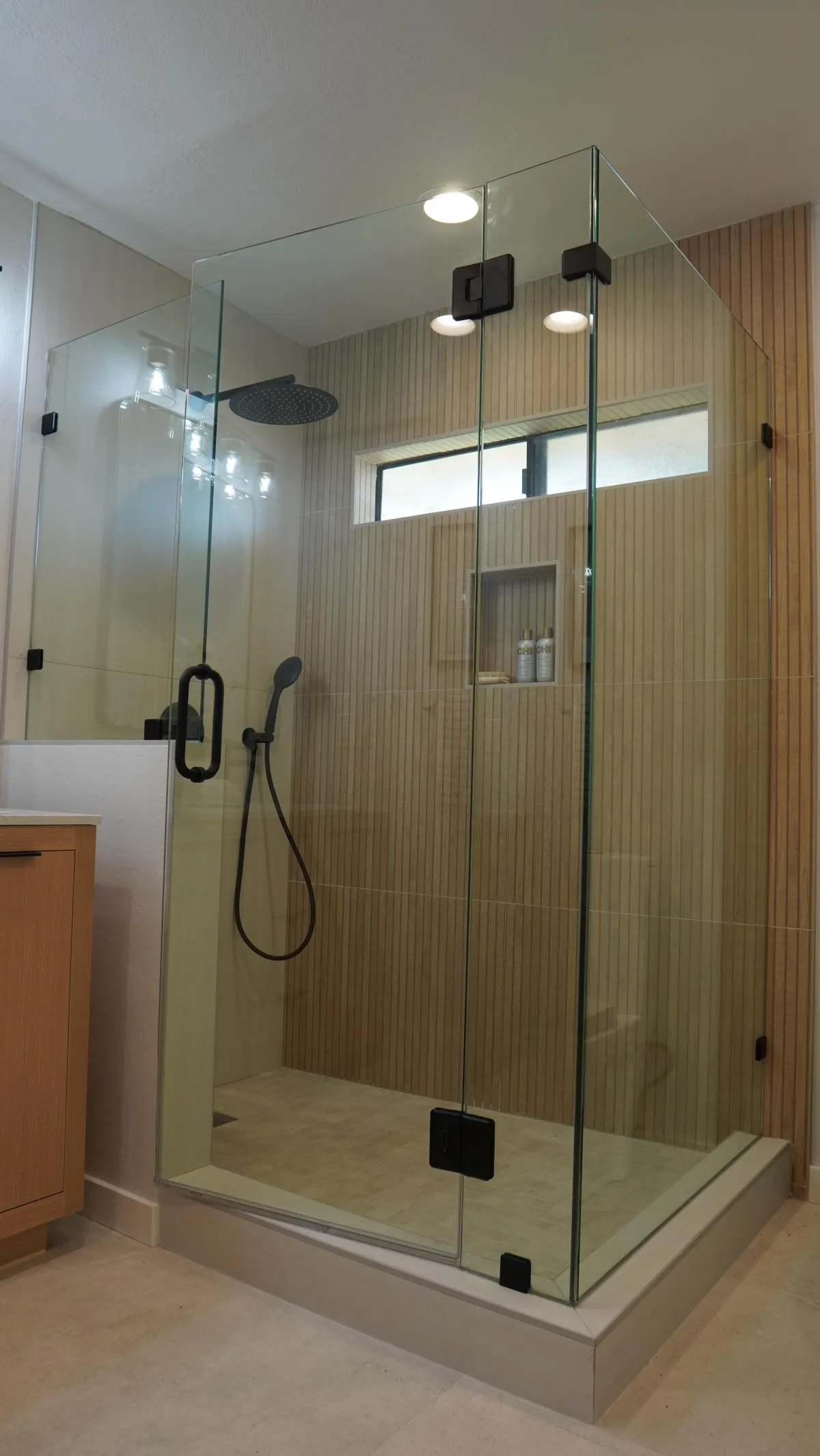 Bathroom remodel featuring a walk-in shower with glass walls, wood like tile, black plumbing fixtures in San Carlos CA.