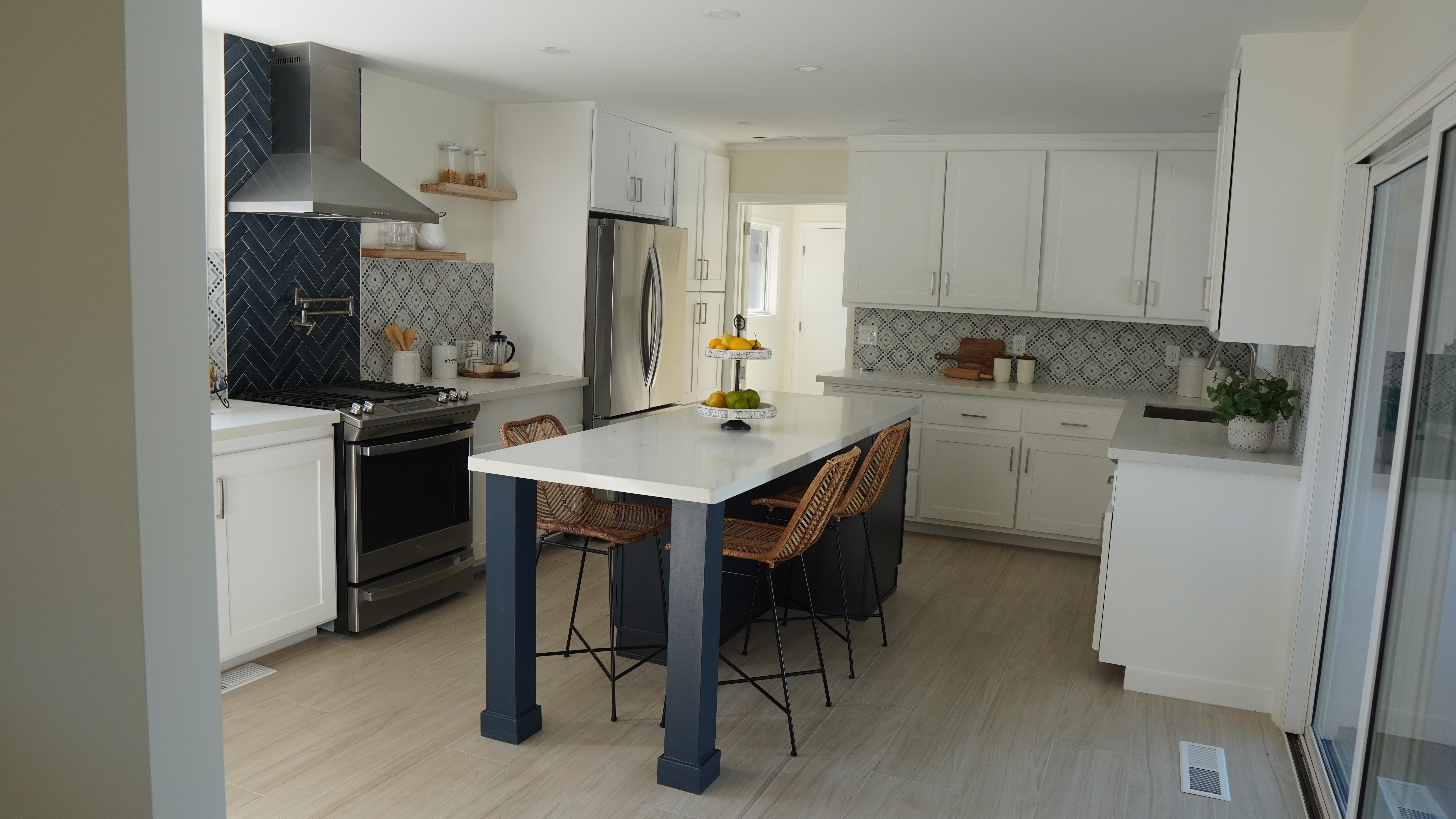 Kitchen remodel on Frenchmans Creek Road in Half Moon Bay, California, featuring custom cabinetry, quartz island countertop, decorative tile backsplash, range hood with blue tile accent, pot filler, and porcelain tile flooring.