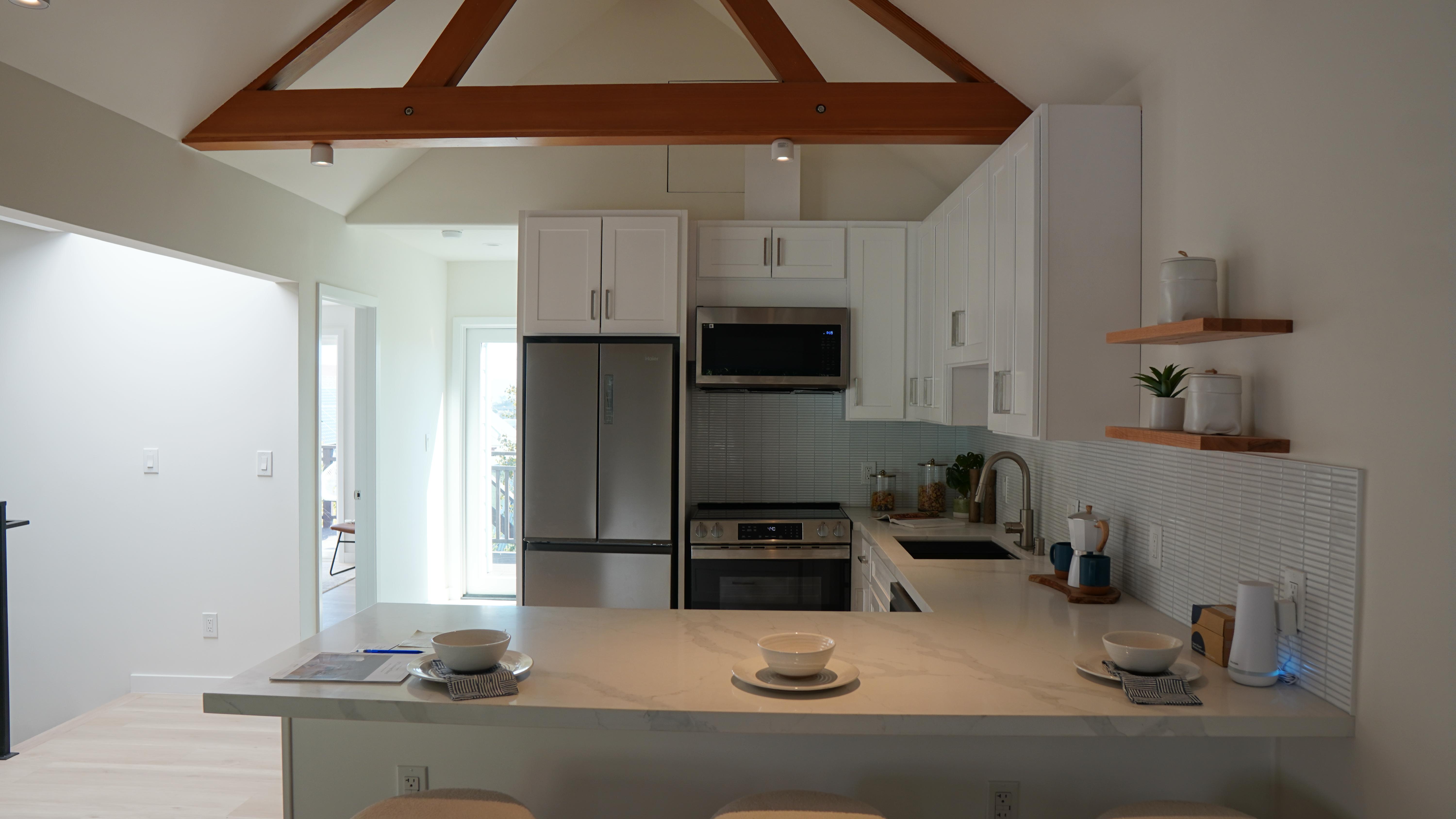 Kitchen Remodel featuring an L countertop area, white cabinets, white subway backsplash tile, floating ceiling beams, floating shelves in San Francisco CA.