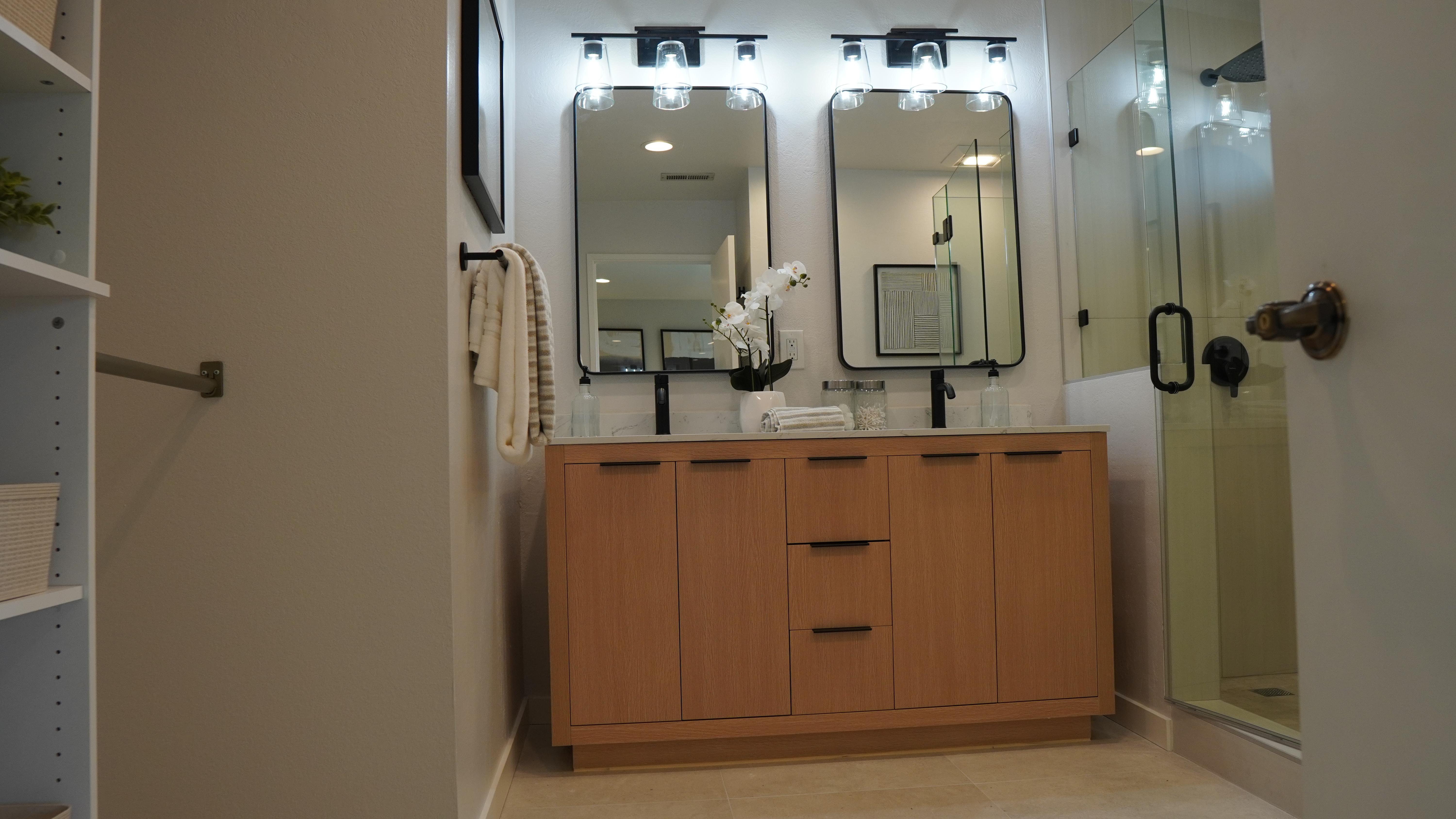Bathroom remodel featuring a double sink vanity with black hardware, black faucets, double mirror an two lights in San Francisco, CA.