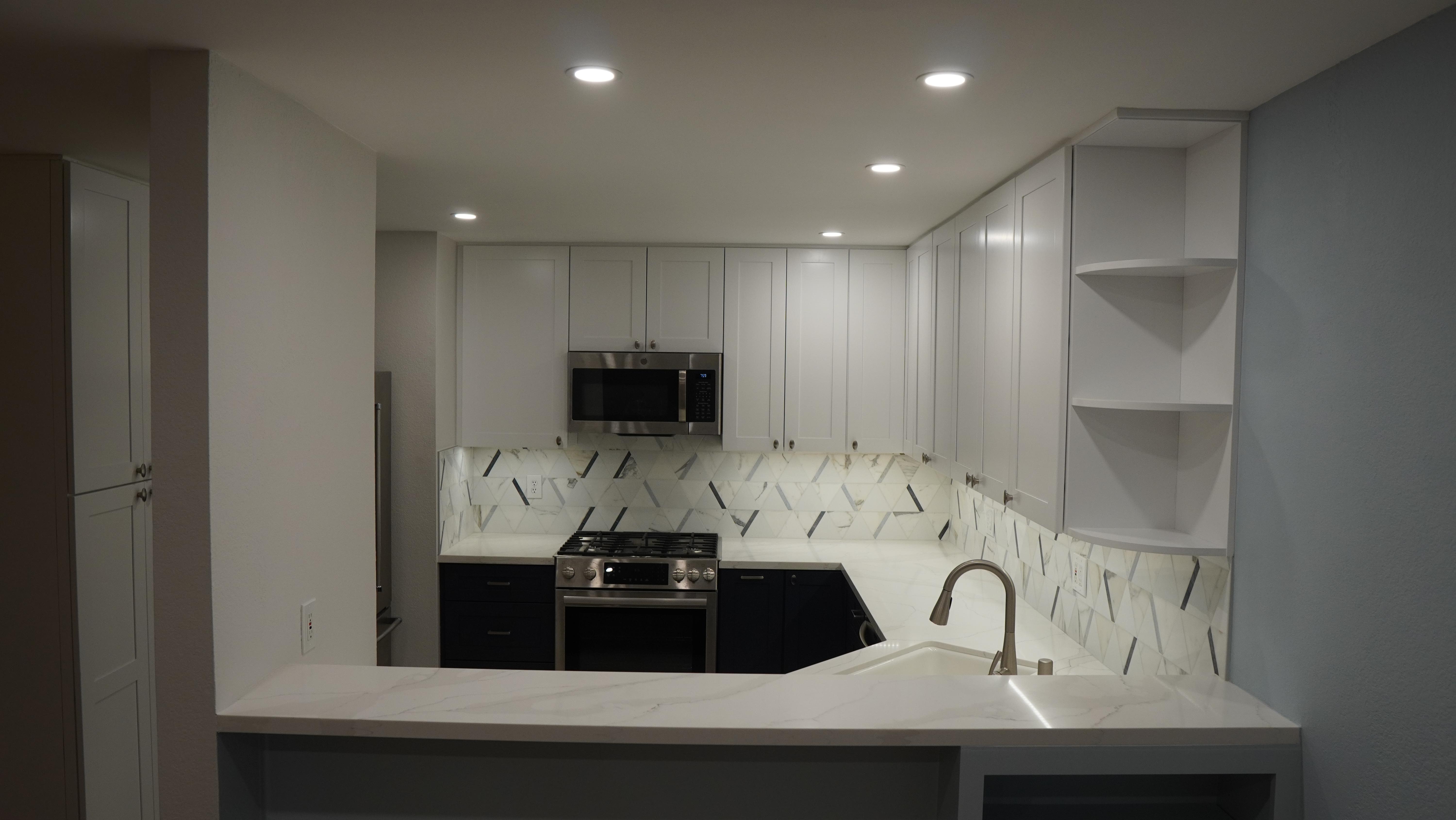 kitchen Remodel featuring white cabinets with button door handles, white quartz, black and white backsplash, ceiling lights on, built-in cabinet shelve in San Carlos CA.