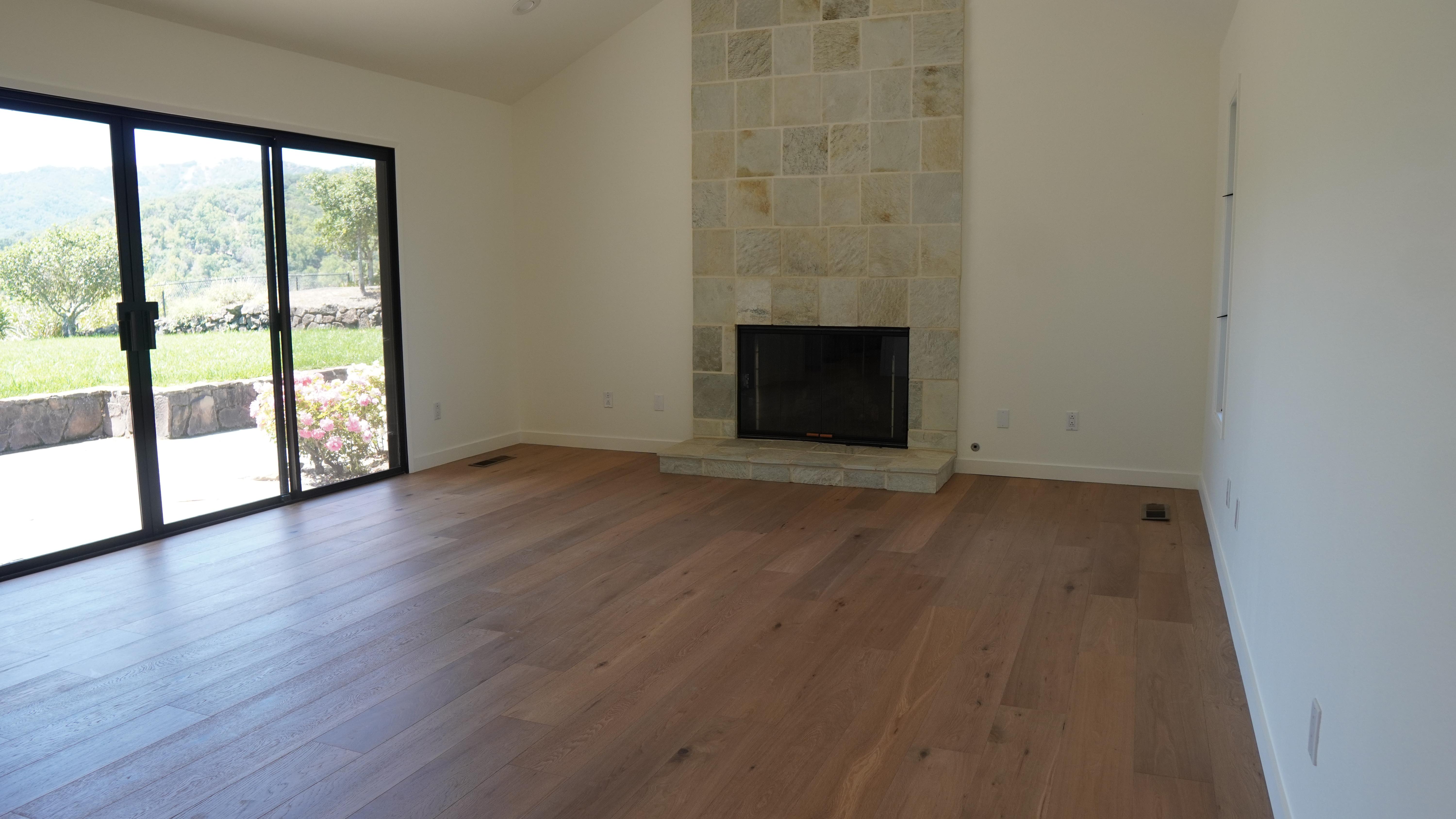 Living room with a chimney decorated with natural stone, and new whit oak hardwood floor in Novato, CA