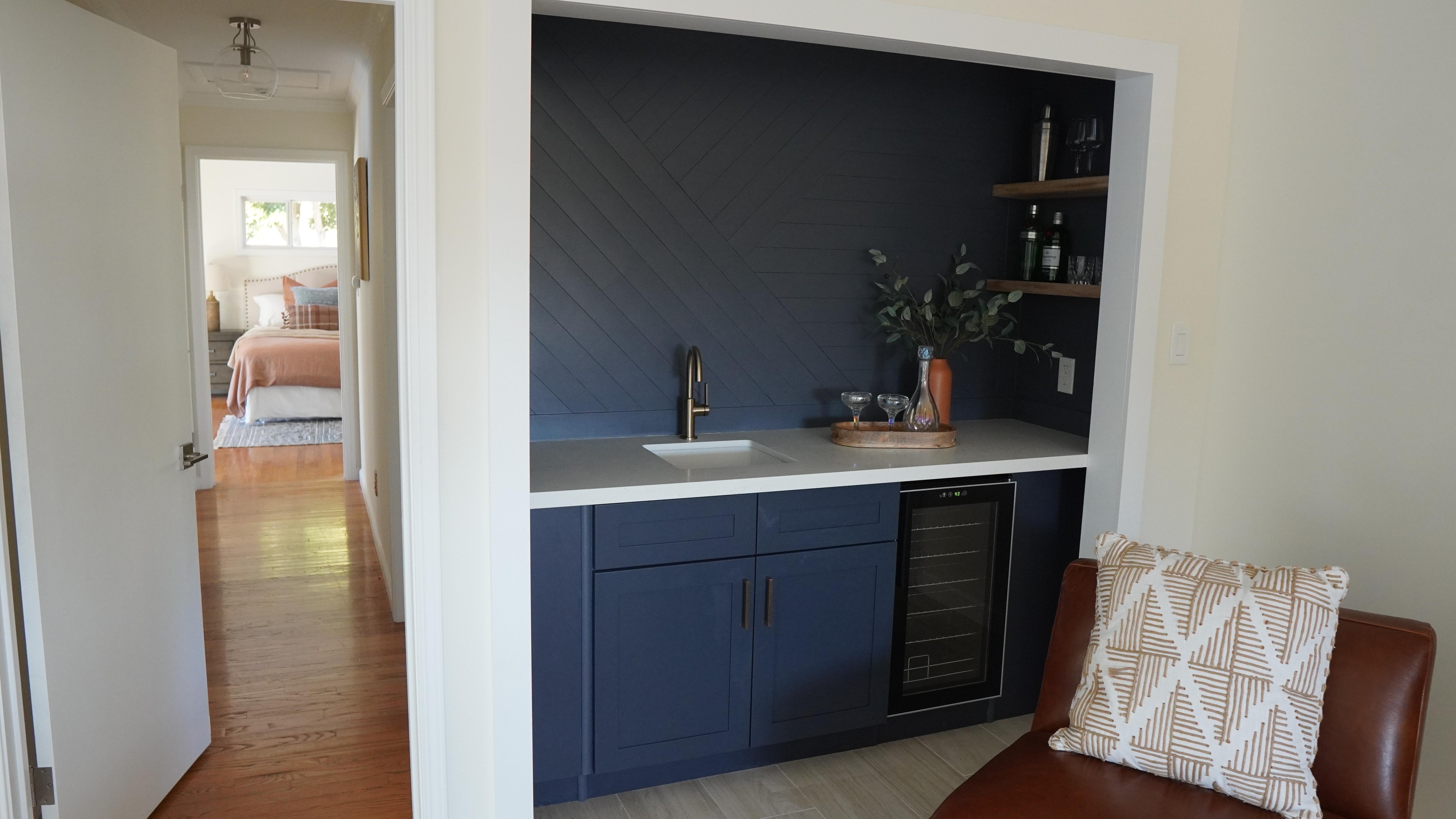 Living room remodel featuring a wet bar with blue cabinets and white countertop with golden faucet in Half Moon Bay, CA.