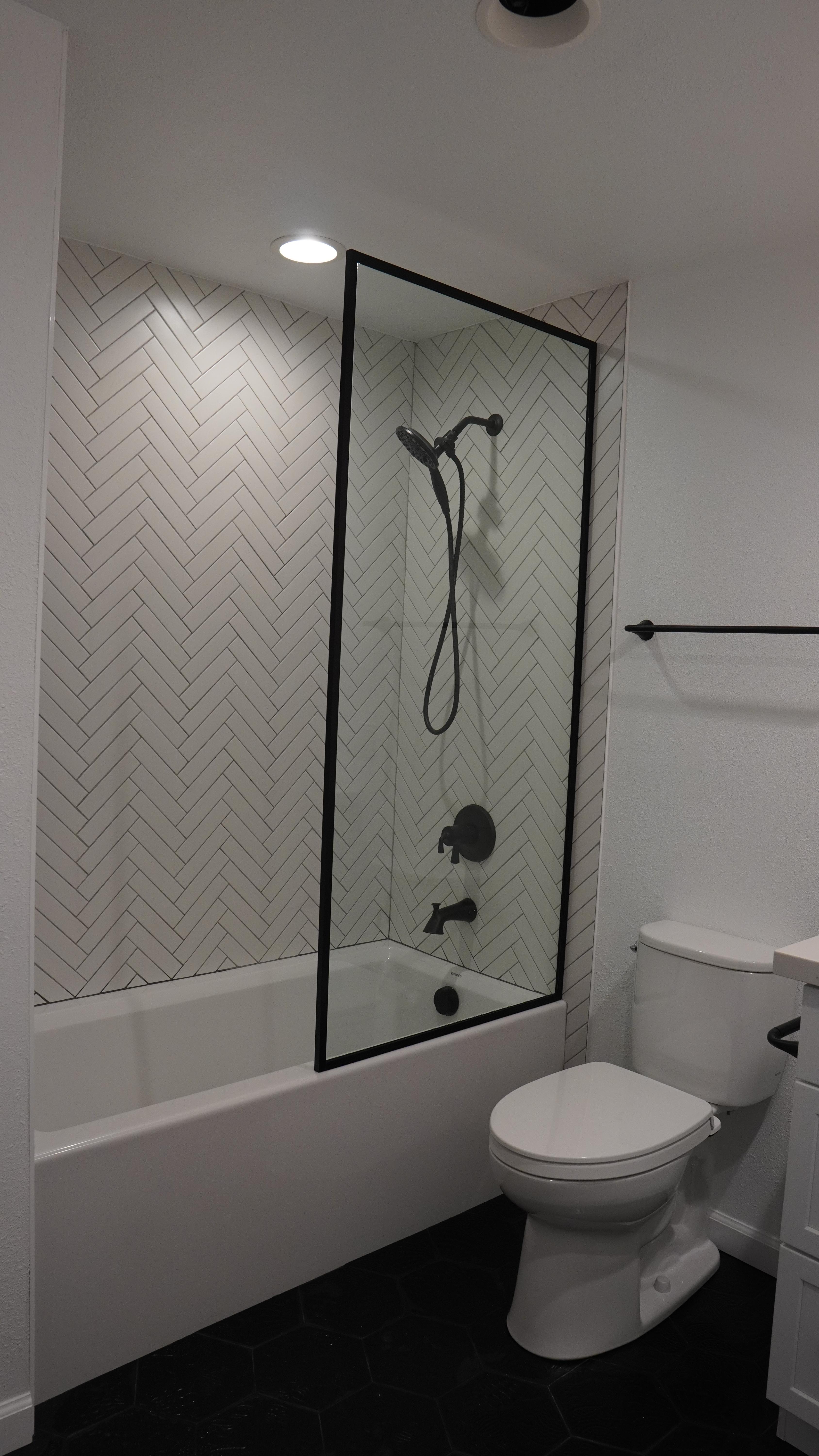 Bathroom Remodel featuring a white tube with chevron tile walls and a glass panel in Oakland CA.