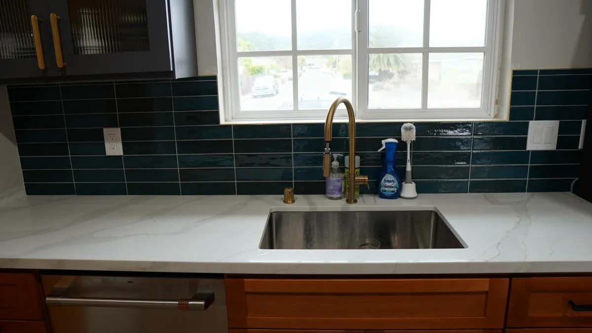 Kitchen Remodel featuring white quartz countertops with grey veins, blu glass tile backsplash, under mount sink, golden sink faucet in Corte Madera, CA.