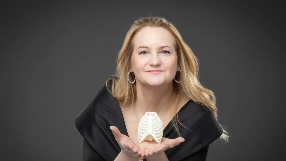 Portrait of Amy Porter, professional flutist and educator, smiling warmly in a bright studio, holding a flute, casual yet professional attire, 1:1 aspect ratio
