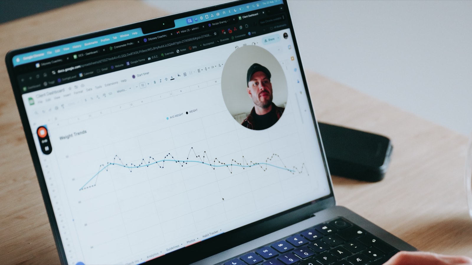Laptop showing a client weight-trend dashboard during an online coaching session
