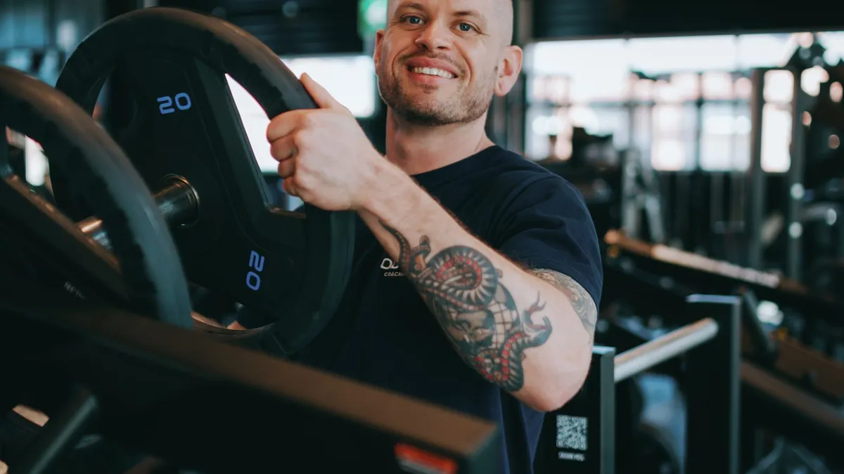 Johan Vesters, nutrition coach, in the gym holding a weight plate, for a post on why under-eating stalls fat loss
