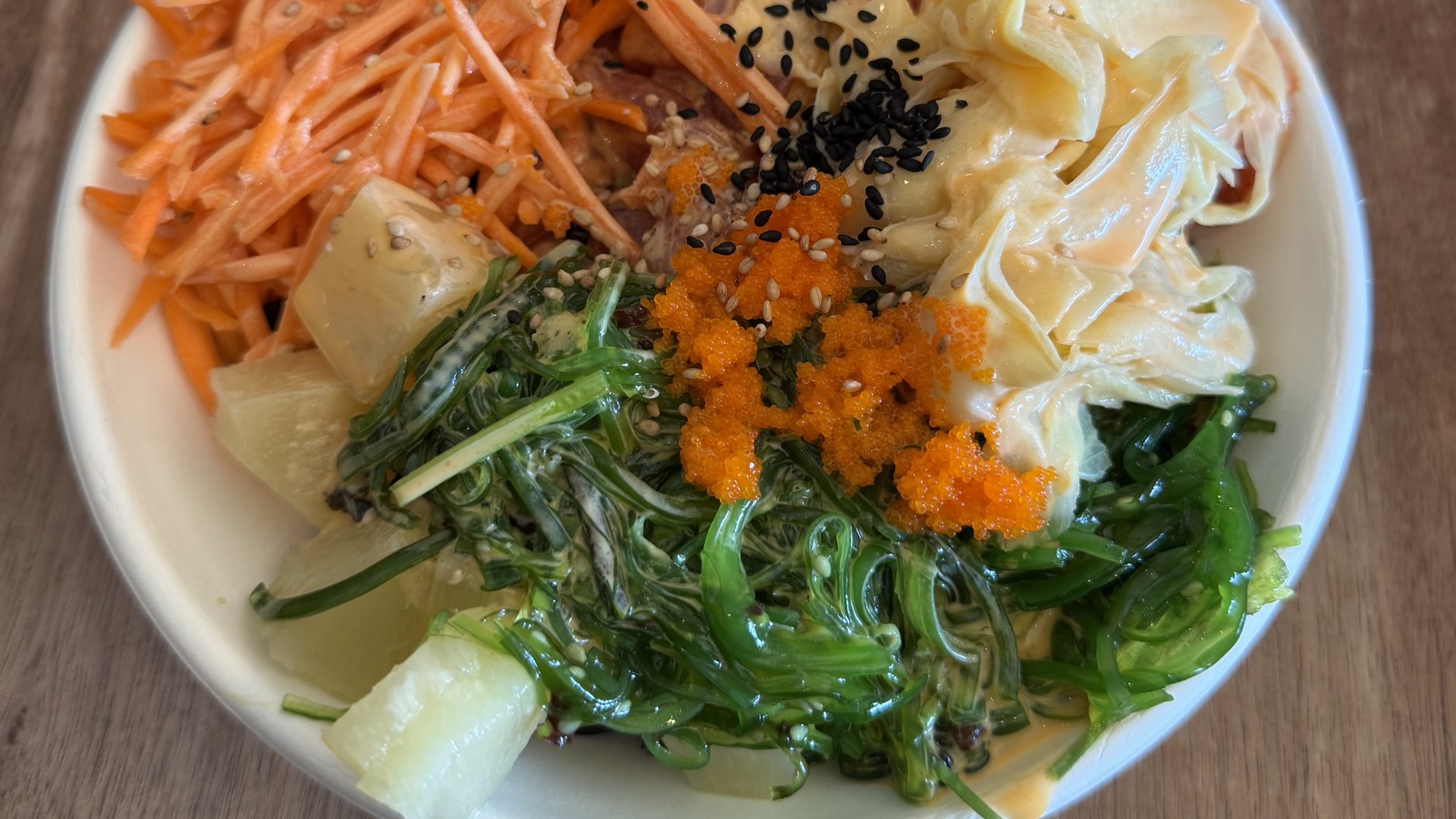 A colorful high-fiber bowl with shredded carrot, seaweed salad, pineapple and sesame seeds