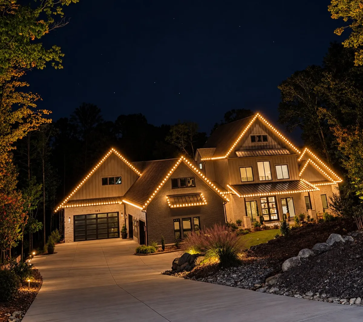 Modern farmhouse at night with warm white lights tracing every gable and roofline