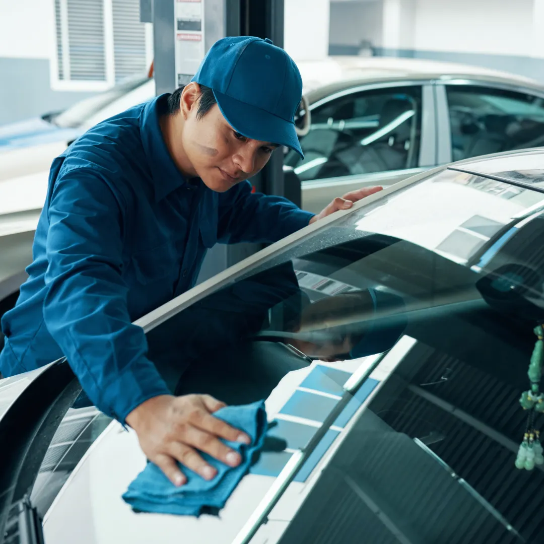 A skilled technician cleaning a windshield with a microfiber cloth, showcasing attention to detail and professional care.