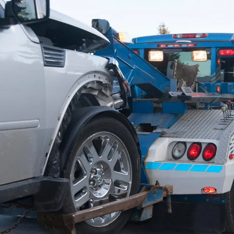Silver car being towed by a tow truck