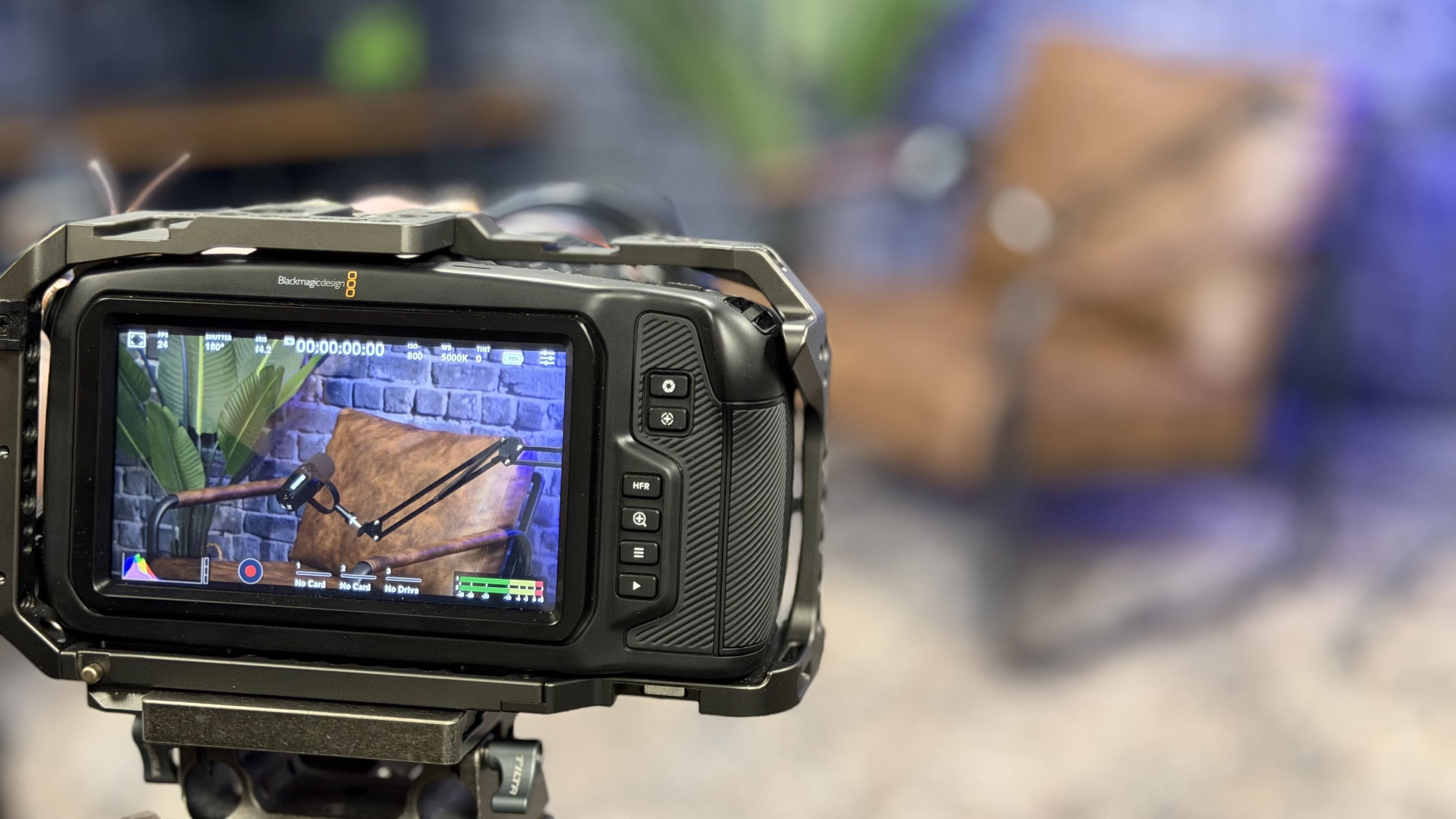 A Blackmagic Design cinema camera on a tripod filming in A Squared's Fairfield, California production studio, with the podcast set framed on its monitor.