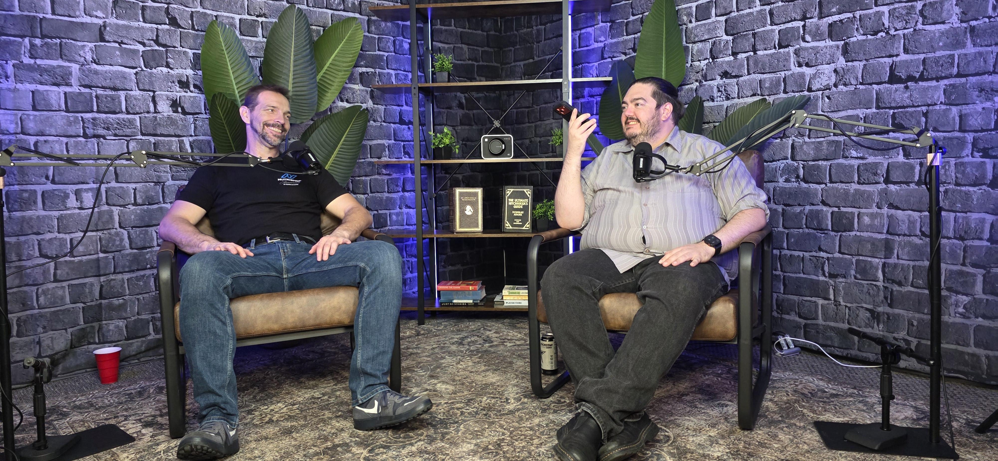 A Squared's podcast and video production studio in Fairfield, California, with two leather chairs, boom-arm microphones and studio lighting against an exposed brick backdrop.