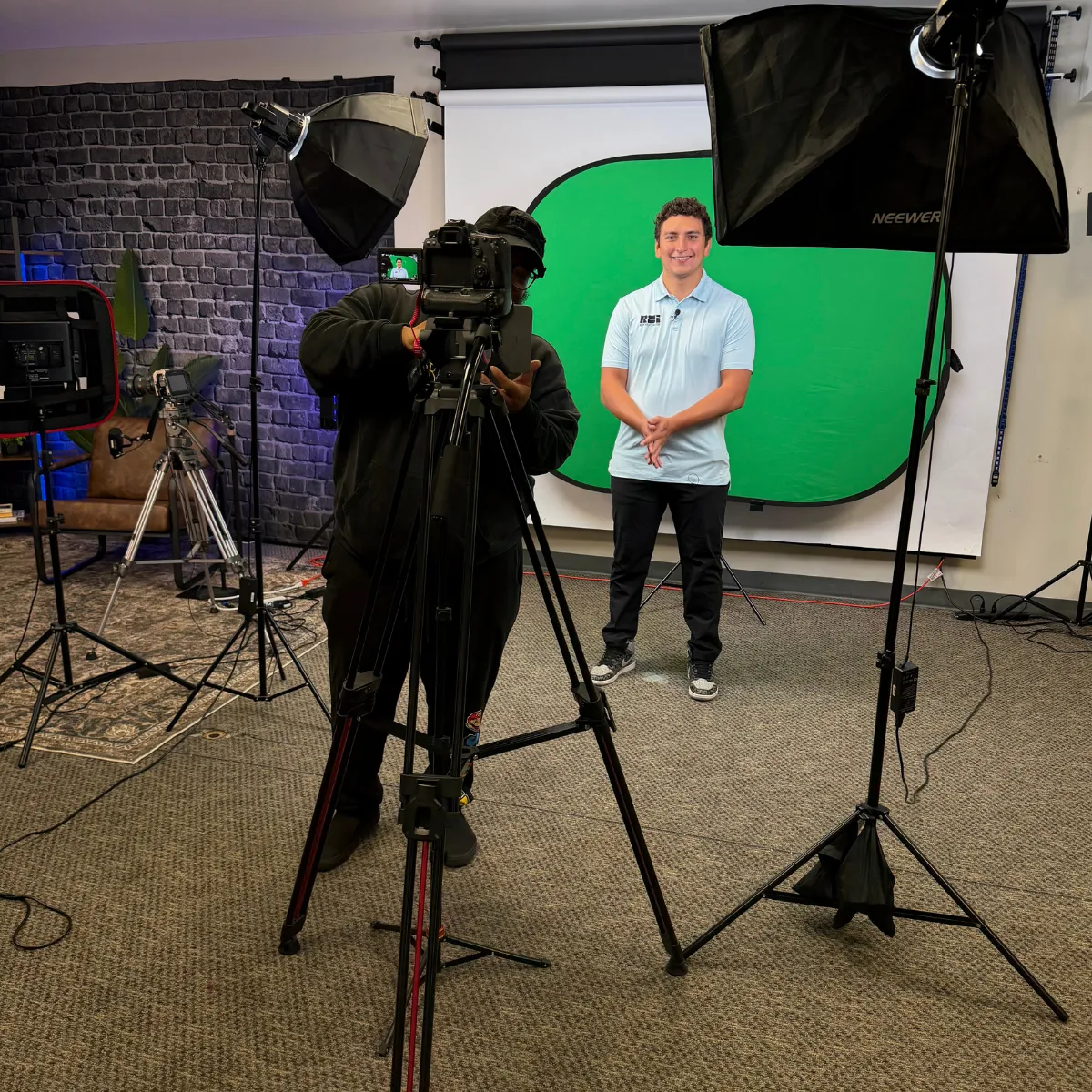 A Squared's studio with a staff member prepping to film against a pop-up green screen in the studio 1 space.