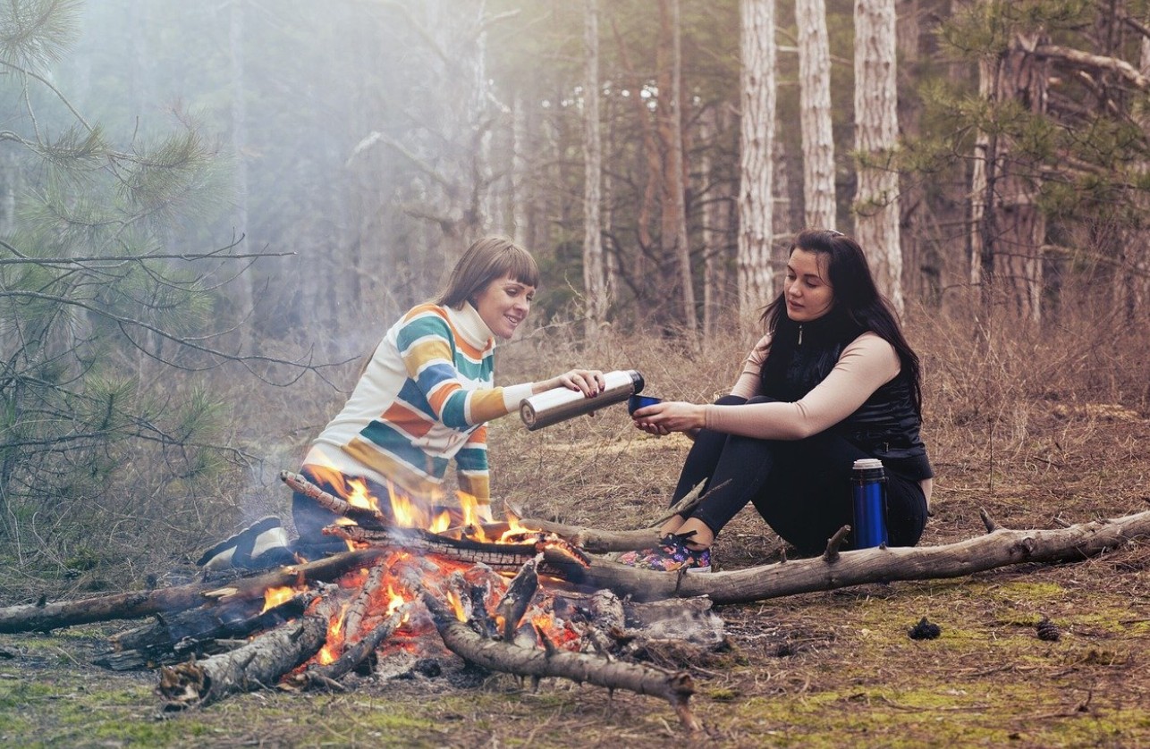 Two women sharing conversation by a campfire — sharing your testimony naturally