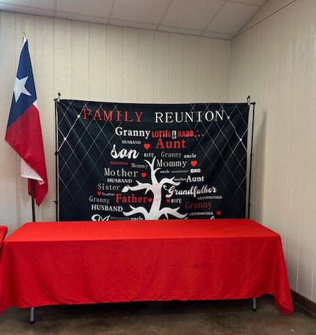A smiling family of four, two parents and two children, gathered around a kitchen table filling out a registration form together.
