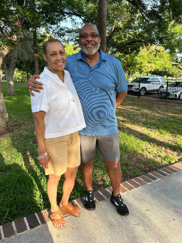 Children of various ages and backgrounds racing in a sack race on green grass, with cheering adults in the background, capturing the energy and excitement of family games at the reunion.