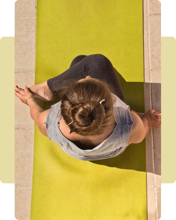 “Top-down view of Katja Reddeker sitting on a bright green yoga mat, practicing mindfulness and relaxation outdoors.”