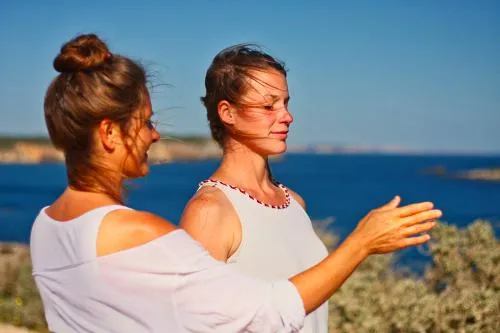 “Katja Reddeker and a Client outdoors near the ocean, engaged in an energy healing session with Katja gently guiding the Client.”