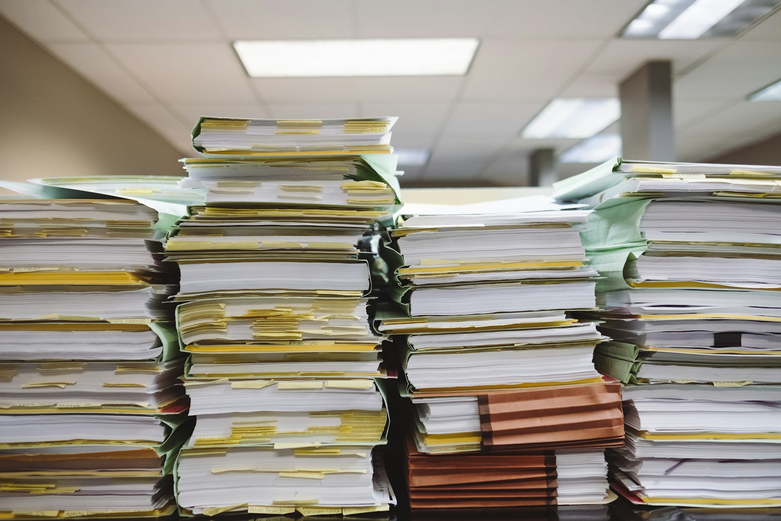 Stacks of tabbed file folders and documents, representing the license, insurance, and background-check paperwork Google requires for the Verified badge