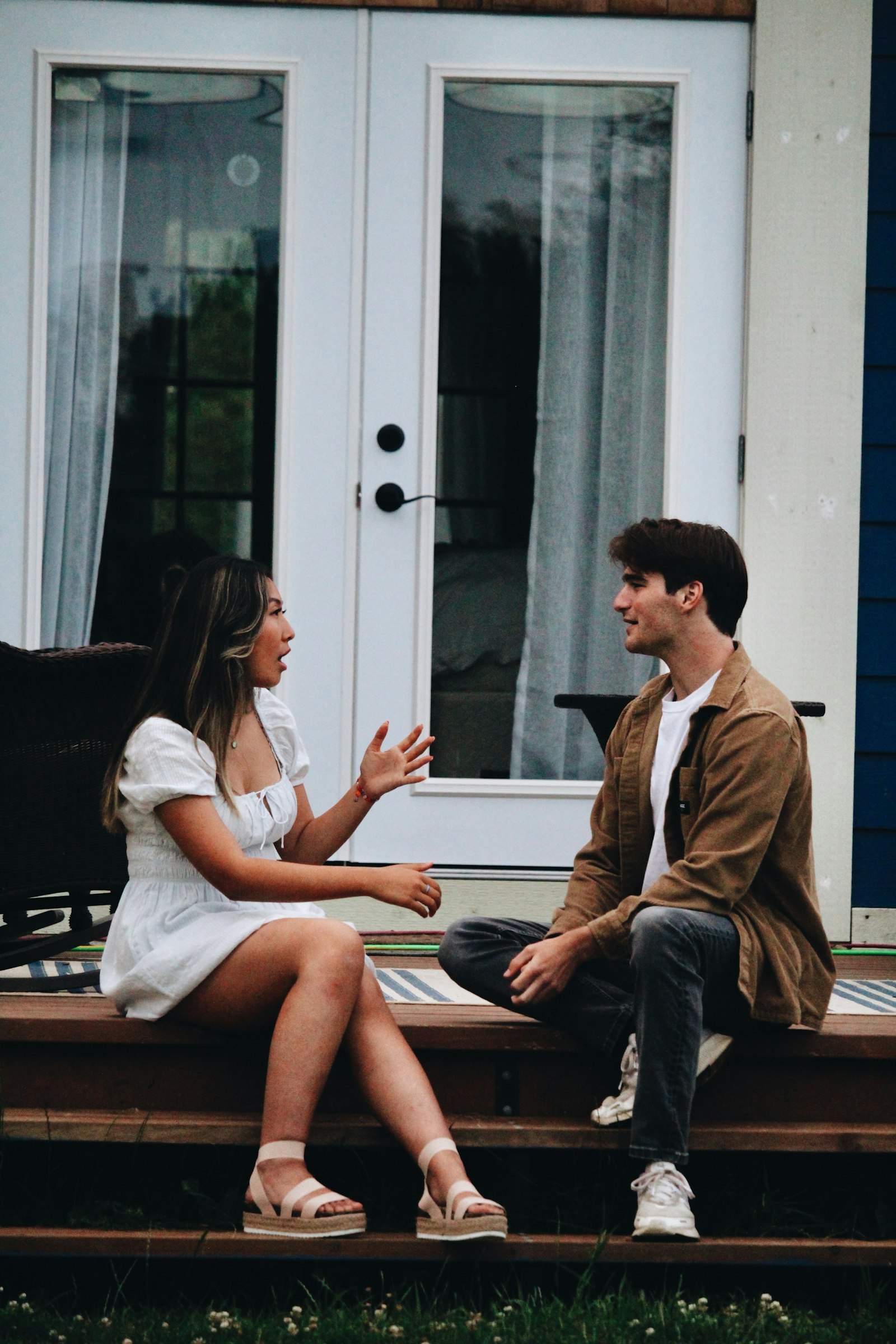 Two neighbors talking on a porch, the word-of-mouth moment behind every referral