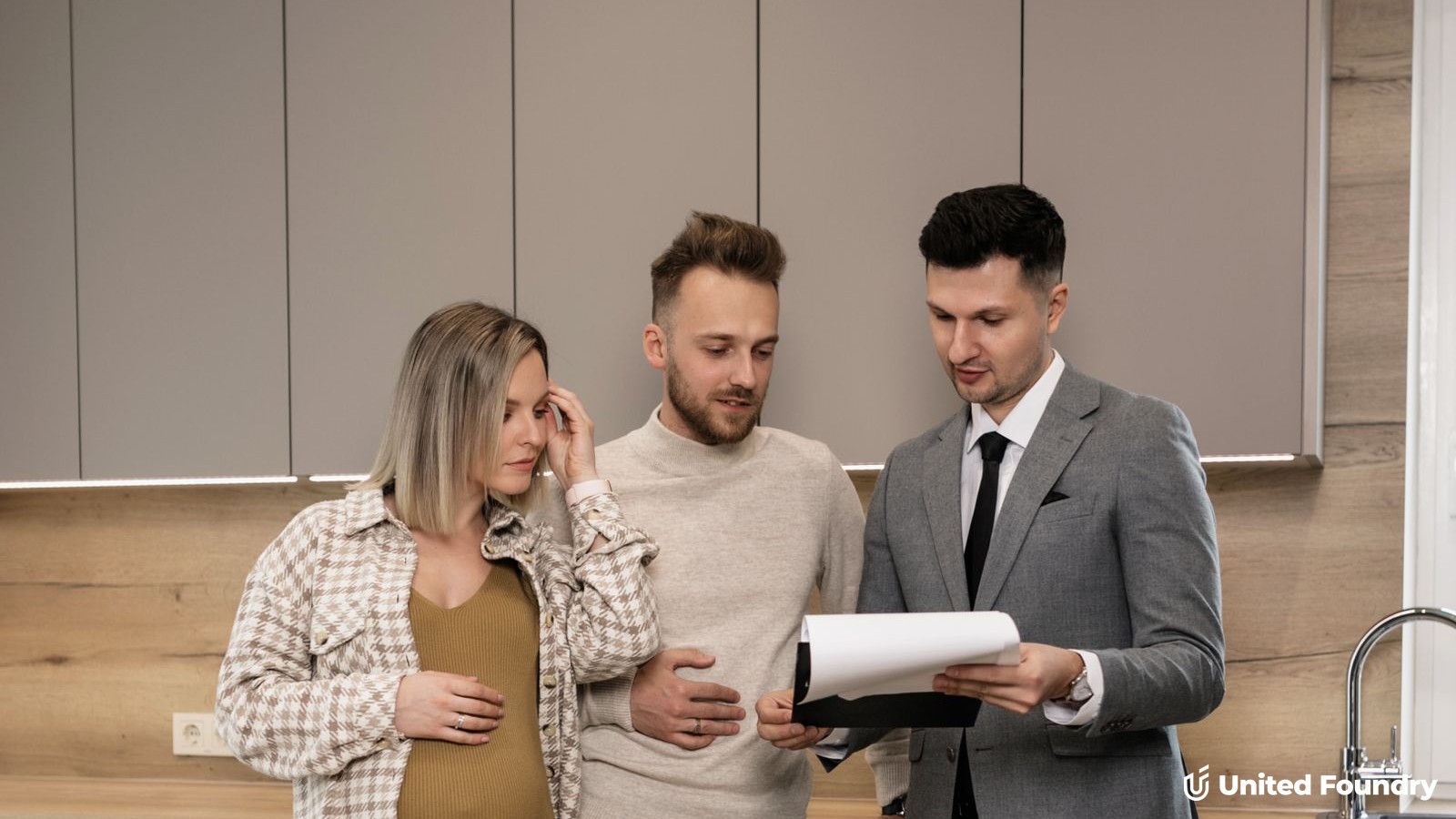 A couple reviewing a written proposal with a contractor in a newly finished kitchen