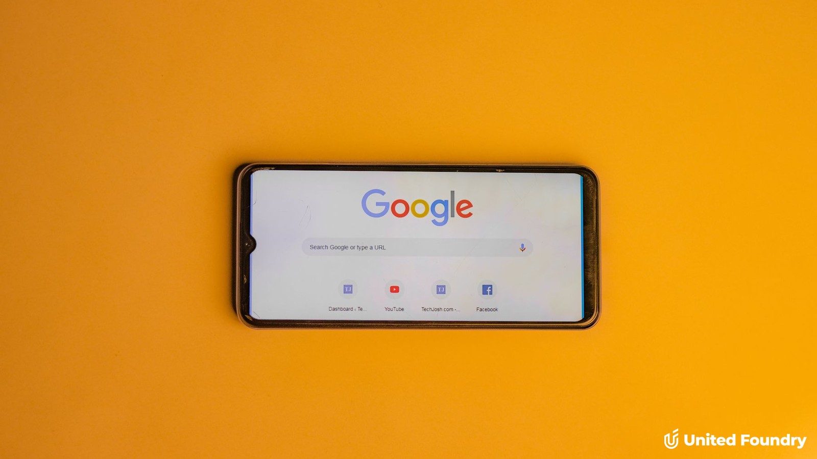 Smartphone showing the Google search page on a gold background, with the United Foundry logo
