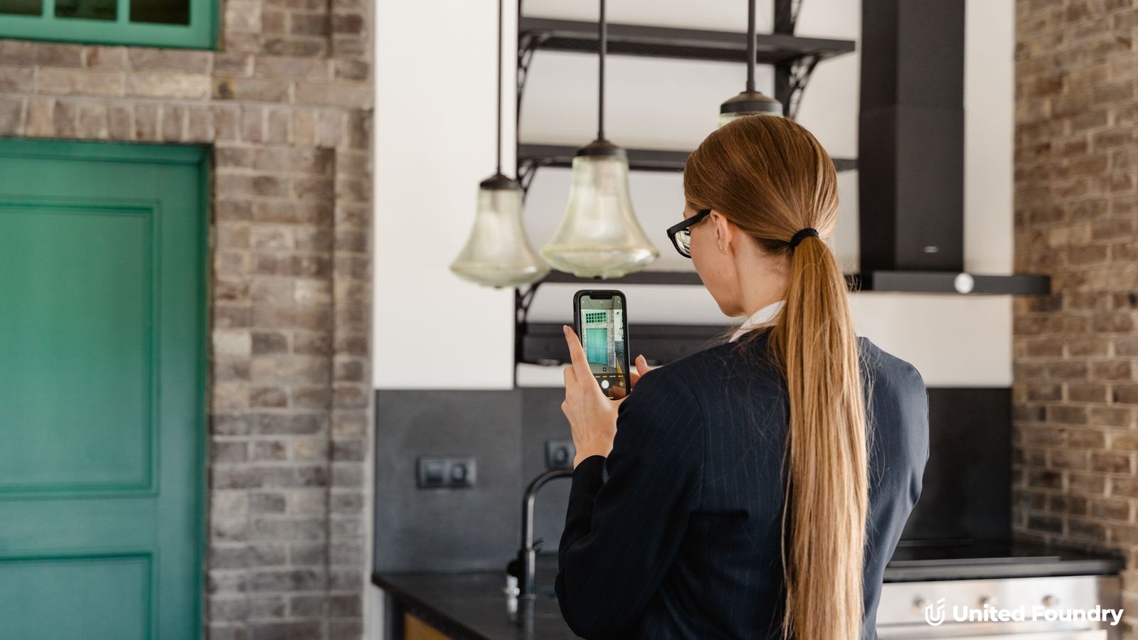 A person photographing a finished kitchen remodel with a smartphone