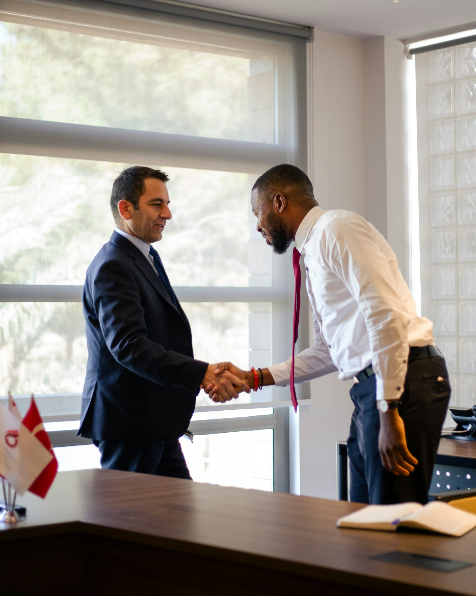 Contractor and client shaking hands across a desk, closing a deal