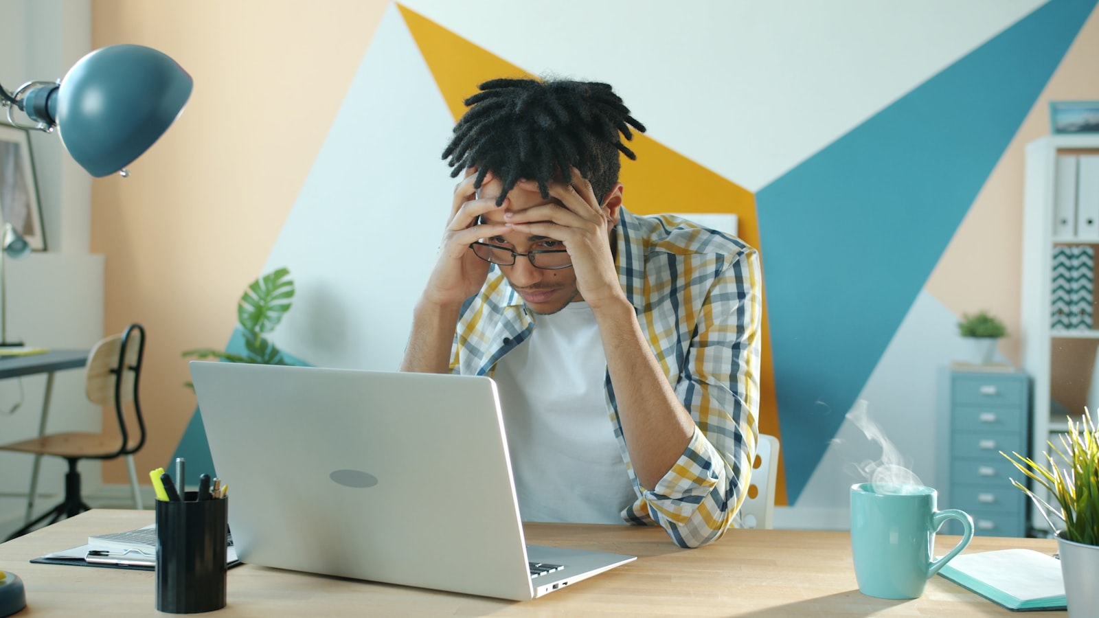 Frustrated business owner holding his head while working on marketing at a laptop