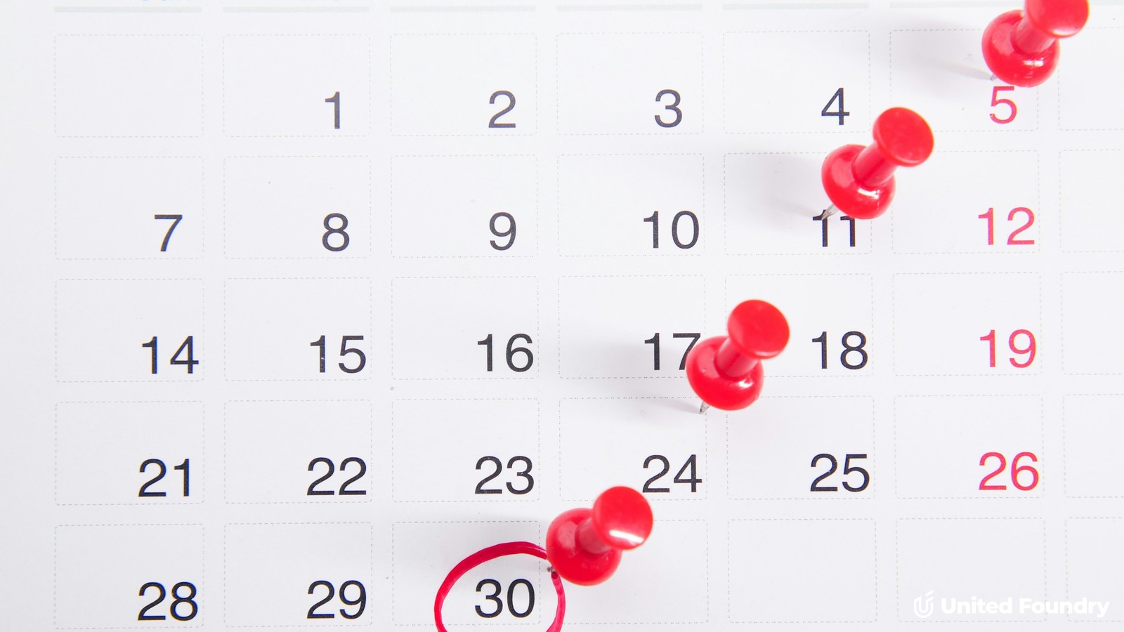 A wall calendar with red push pins marking dates and the 30th circled in red, representing an LSA reverification deadline