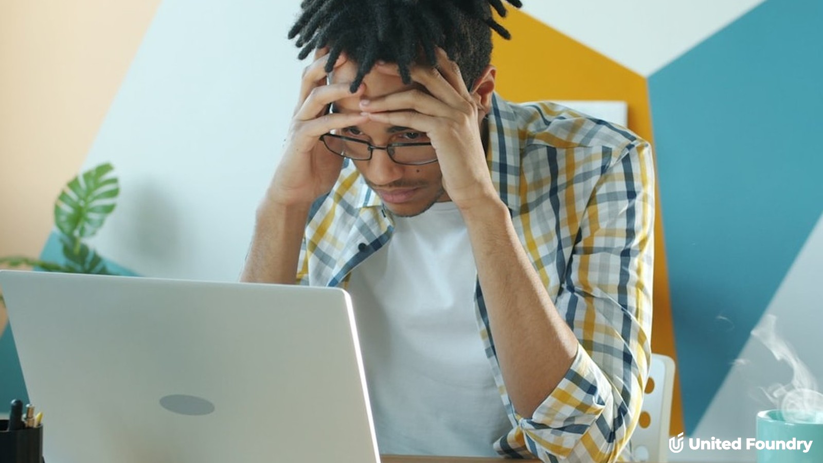 Frustrated business owner holding his head while working on marketing at a laptop