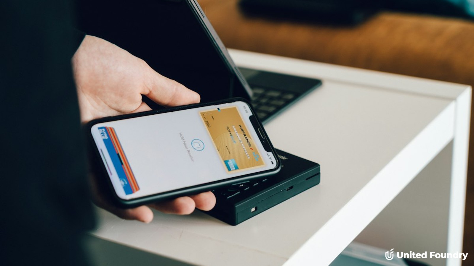 Person holding a smartphone with a contactless payment card ready near a card reader