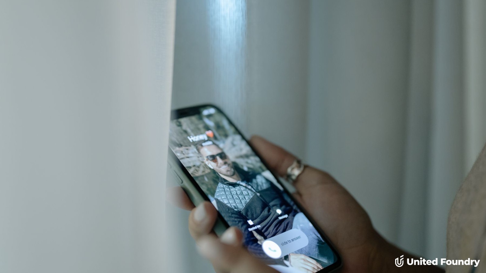 Hand holding a smartphone showing an incoming call notification