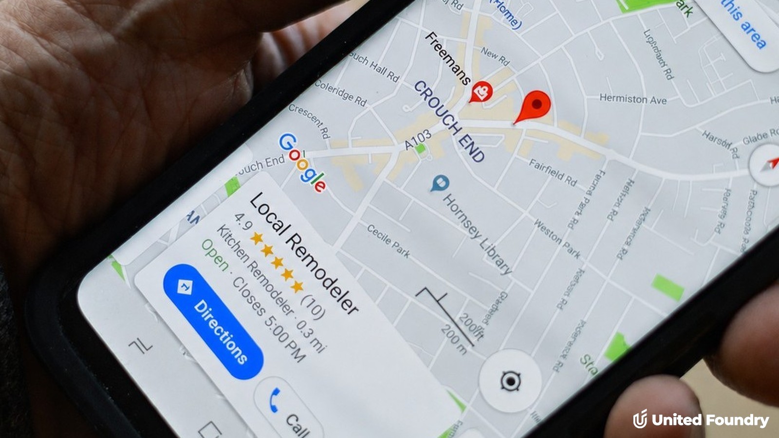 Hand holding a phone showing a Google Maps local search with a business listing, star rating, and call button — the Google Business Profile in action