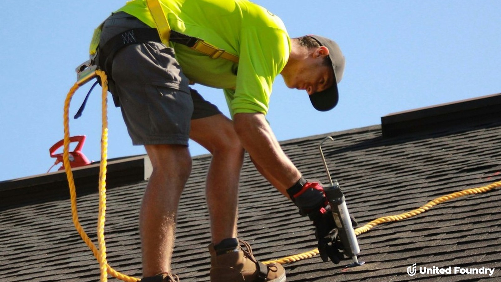 Roofer in safety harness sealing shingles on a residential roof