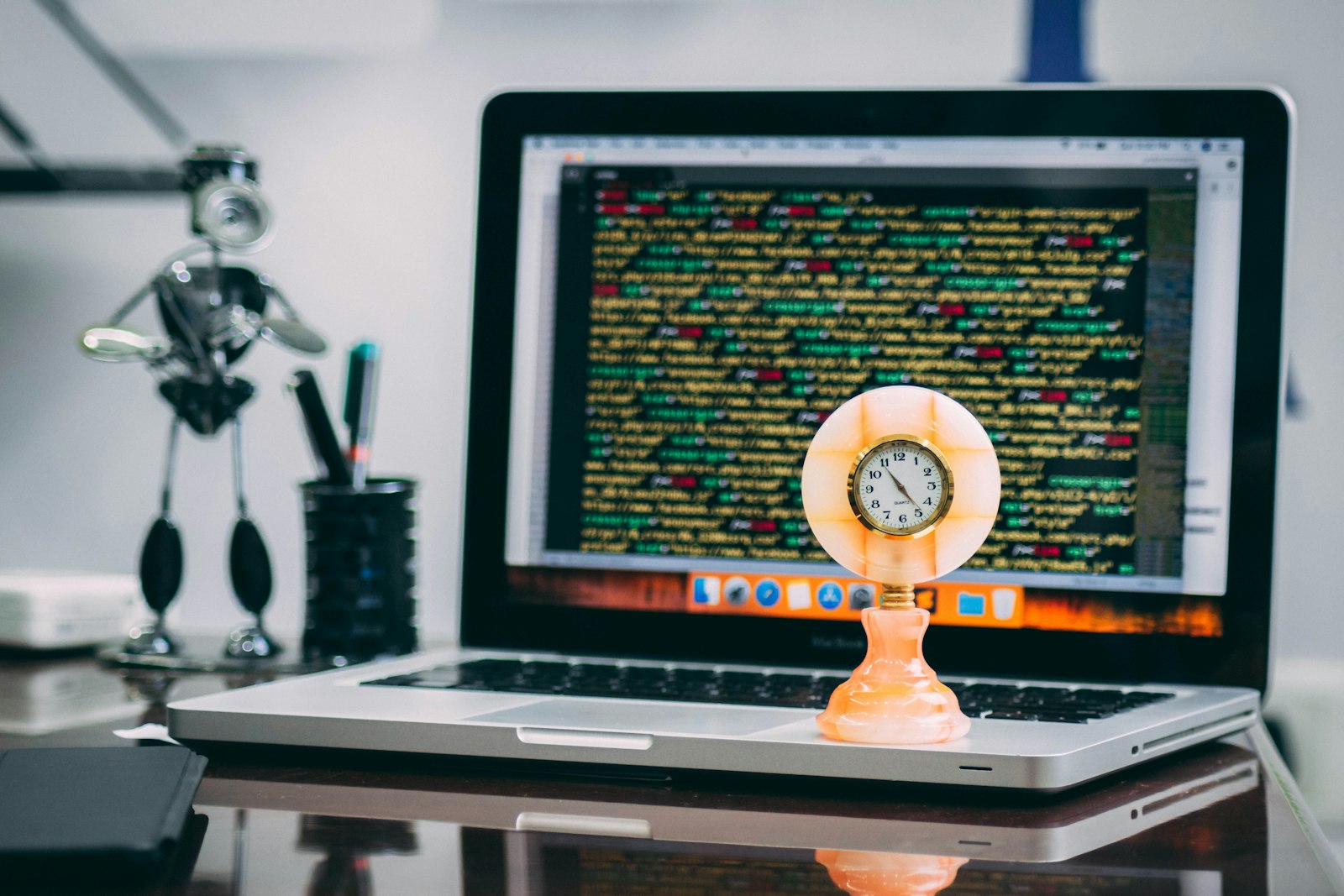 A clock sitting on top of an open laptop displaying code, representing website load speed
