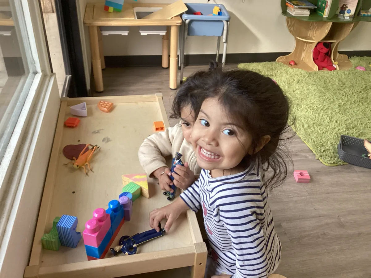 Smiling child playing with educational toys in a childcare classroom