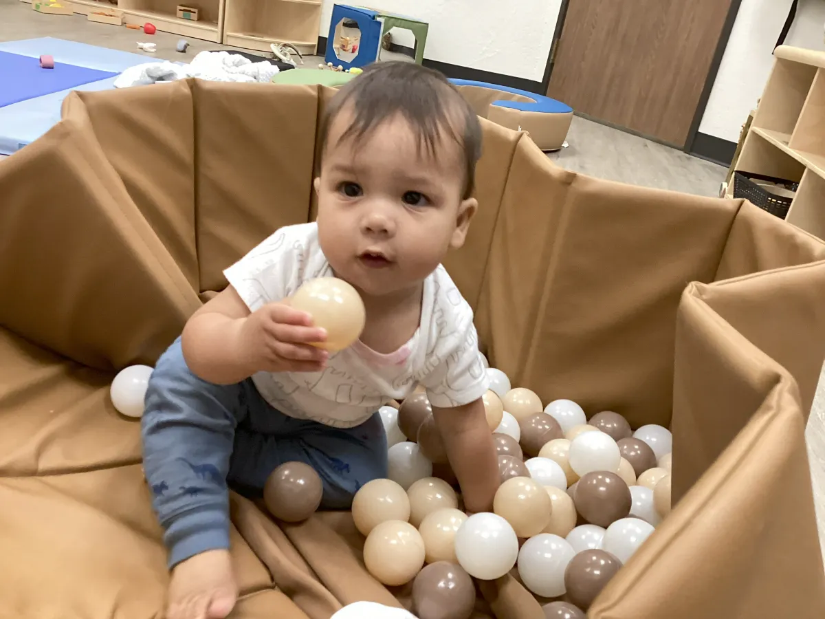 Baby playing in a ball pit at a childcare center