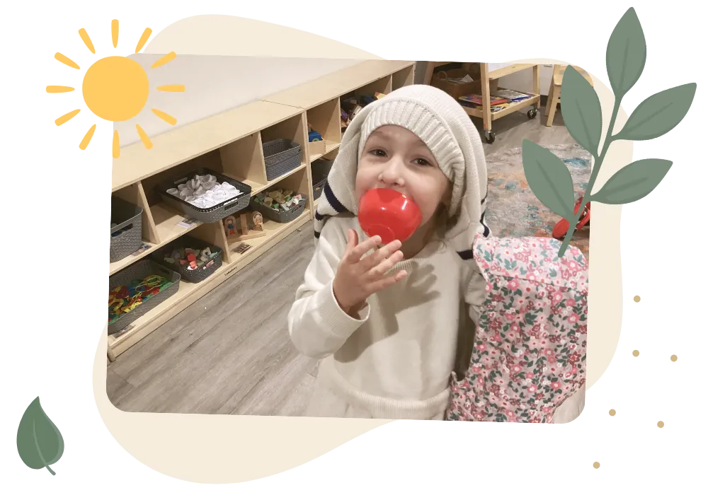 Smiling child playing with a red toy apple in a childcare classroom