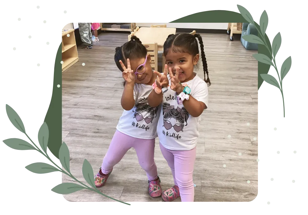 Two smiling children posing together in a childcare classroom
