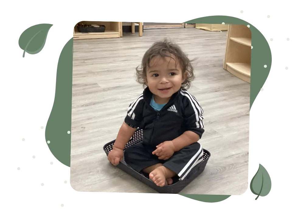 Smiling toddler sitting and playing in a bright childcare classroom