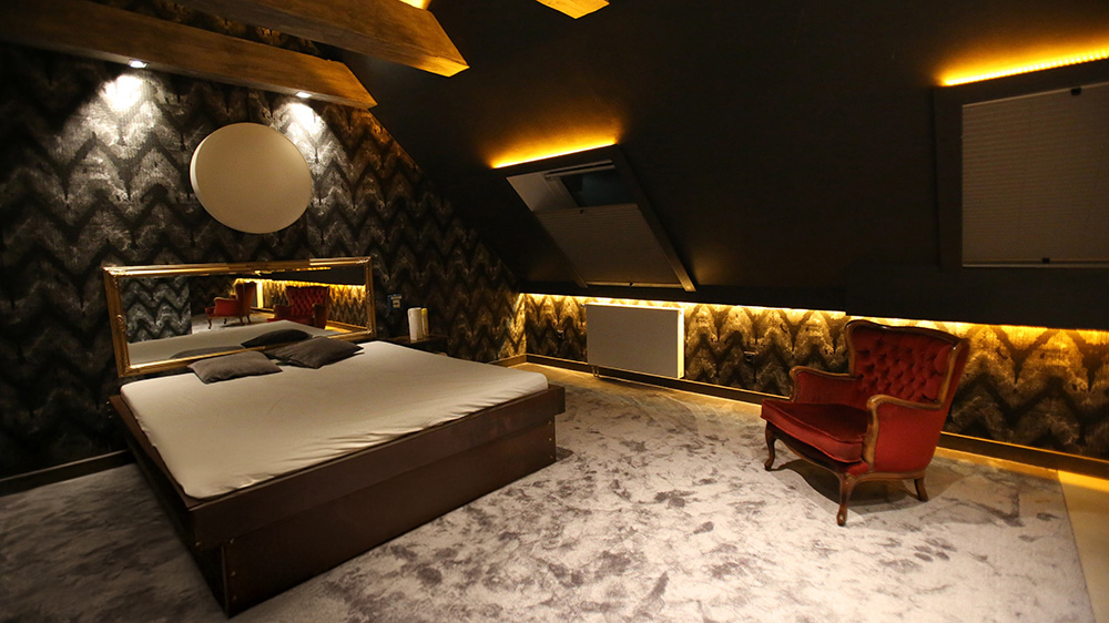 Exklusives Ambiente im Villa Amore Düsseldorf mit gemütlichem Bett, indirekter Beleuchtung und elegantem Sessel