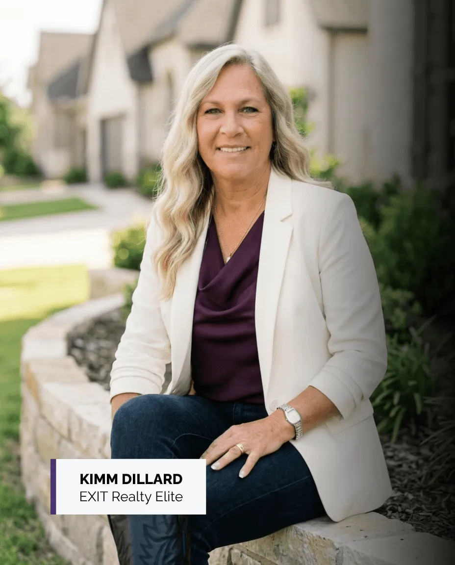 Kimm Dillard, REALTOR® with EXIT Realty Elite, seated outdoors in a cream blazer and plum blouse.