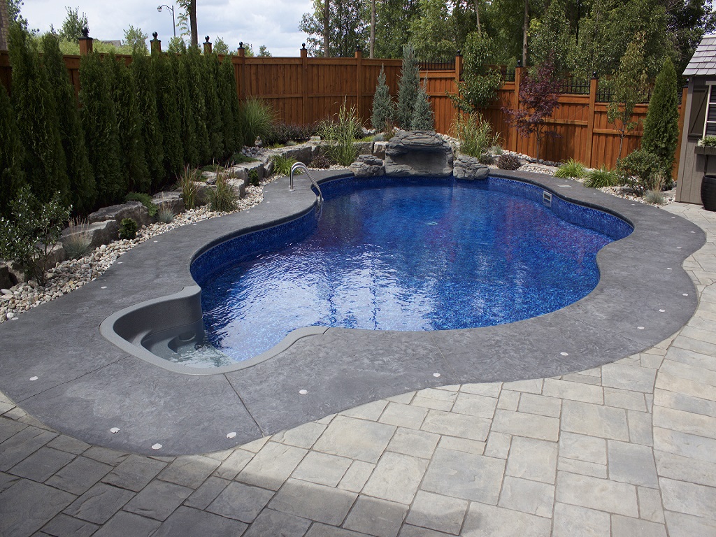 Decorative concrete pool deck with landscaped backyard swimming pool in Hamilton Ontario