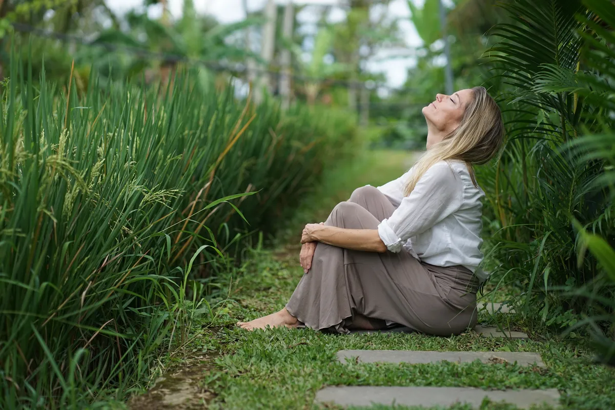 Fanny sitting among green plants, face turned to the sky
