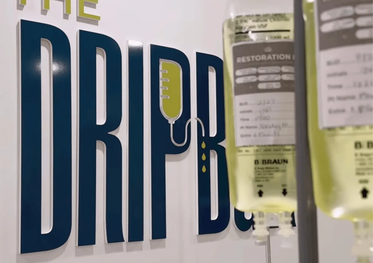IV drip bags hanging beside The DRIPBaR logo wall