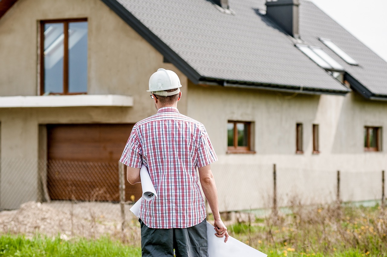 a contractor walking onto the jobsite with a set of plans and wearing a hardhat